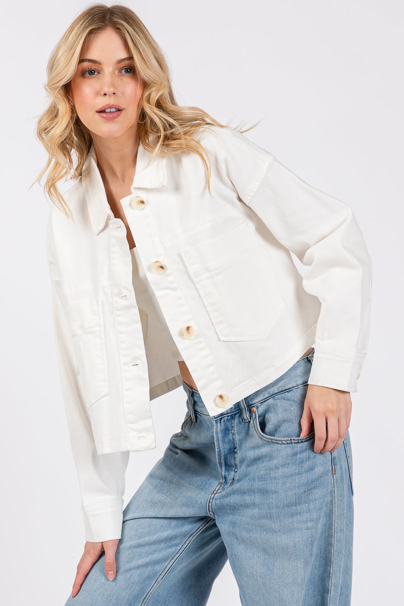 Cropped denim-style jacket in white with button-down front and front patch pockets, styled with relaxed jeans.
